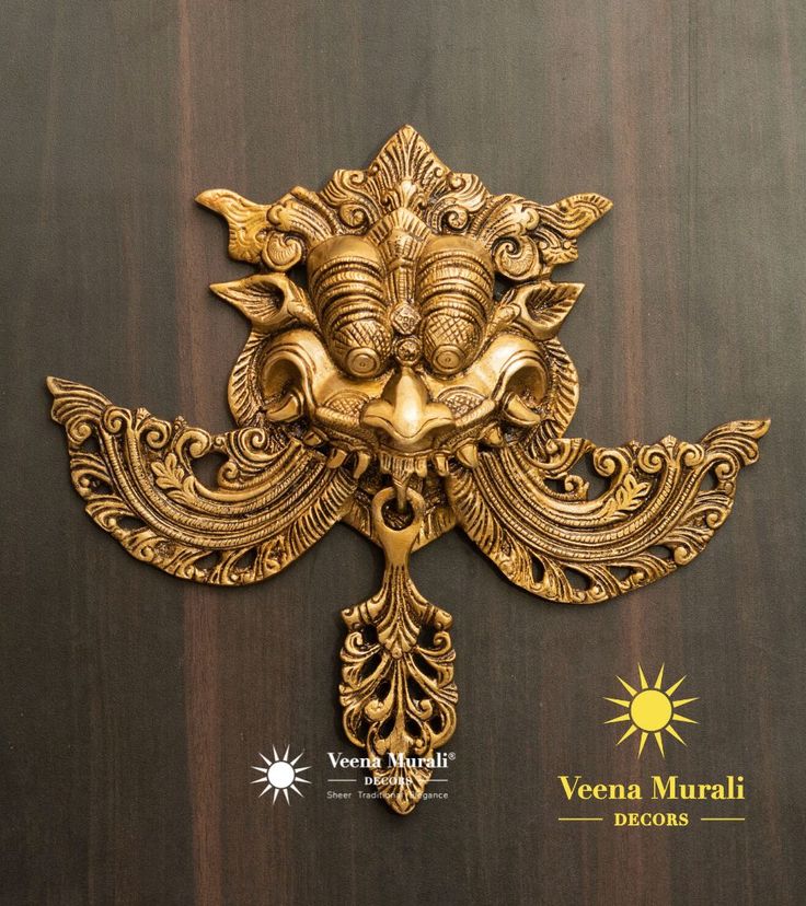 an intricately designed brass door knocker on a wooden surface with the words veena munnii written below it