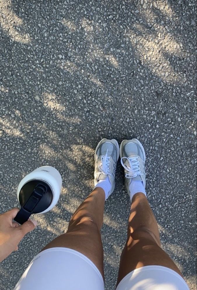 a person standing on the ground with their feet in a coffee cup and wearing tennis shoes