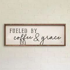 a wooden sign that says fueled by coffee and grace on the side of a white brick wall