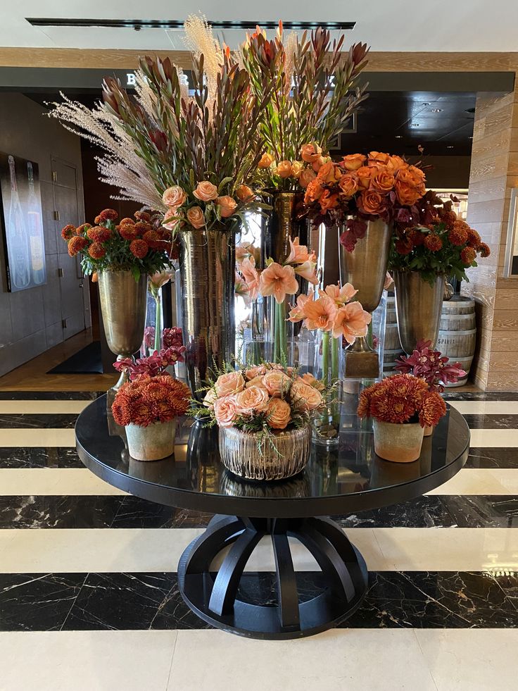 a table topped with vases filled with flowers on top of a black and white striped floor