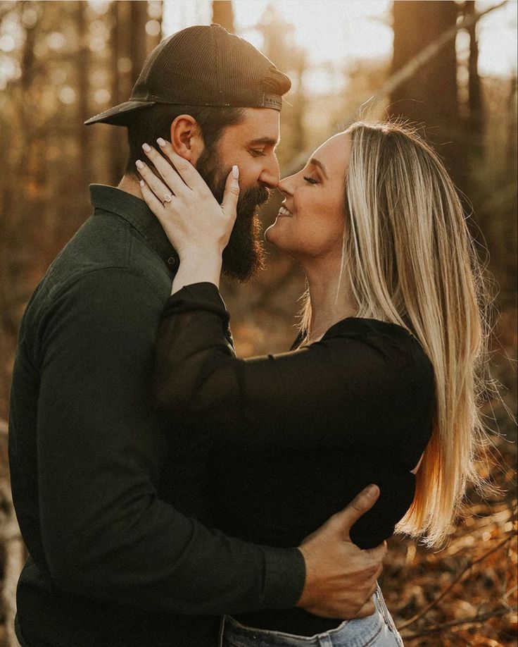 a man and woman are kissing in the woods with each other while they stand close together