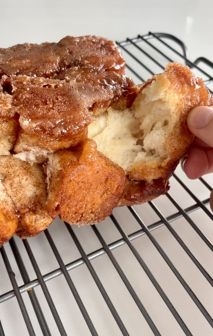 a person is holding up a doughnut on a wire rack with some powdered sugar