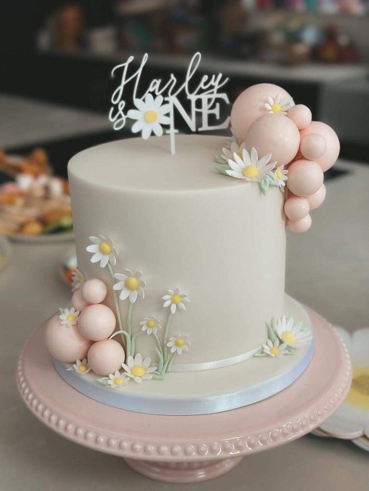 a white cake with flowers and balloons on top