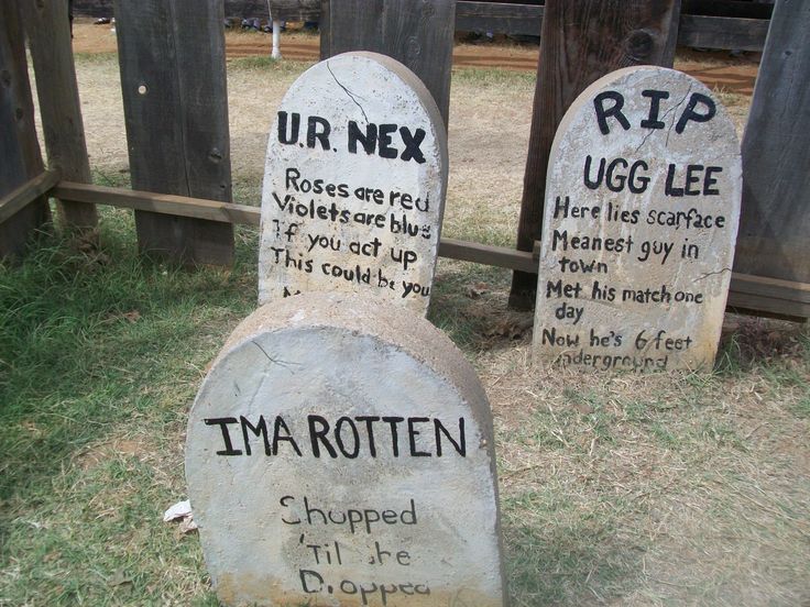 two stone headstones with writing on them in front of a wooden fence and grass