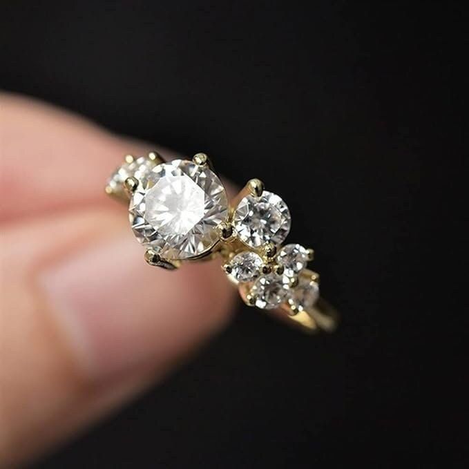 a person holding a ring with three diamonds on it's side, in front of a black background