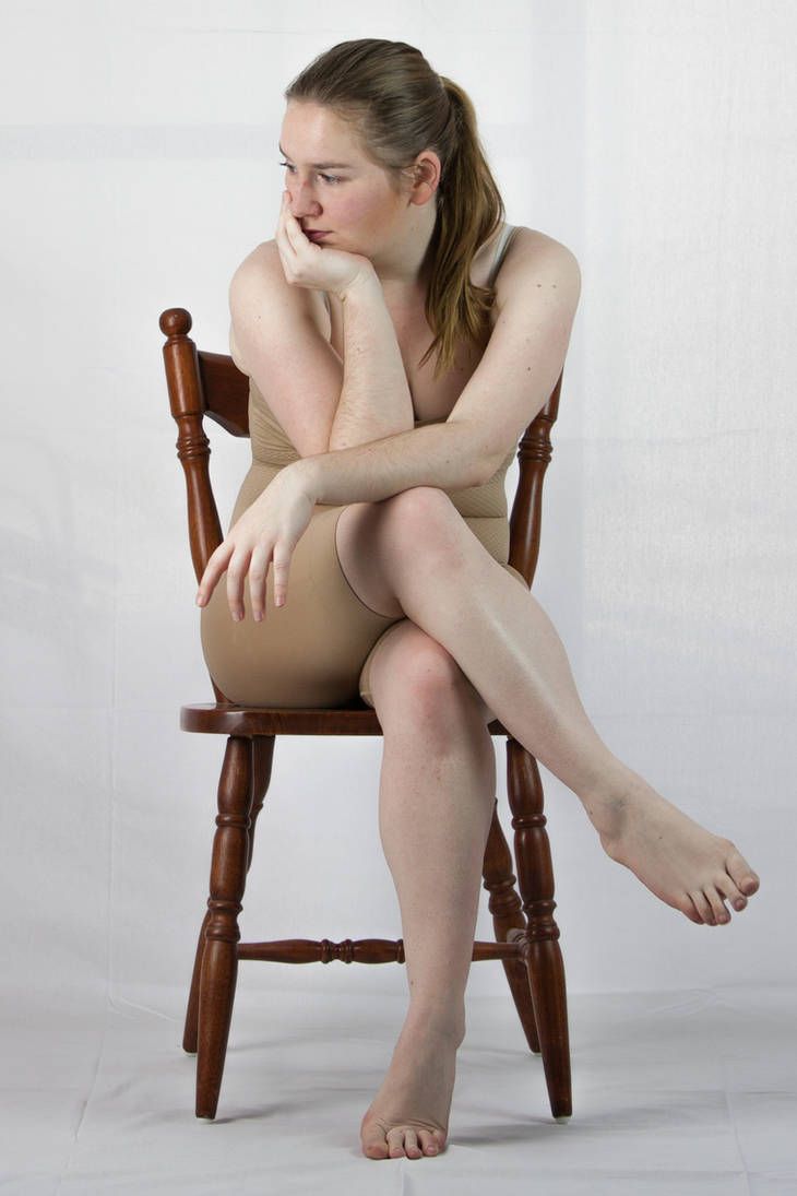 a naked woman sitting on top of a wooden chair