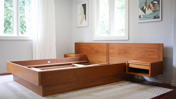 a bed frame with drawers on each side in a living room next to a window