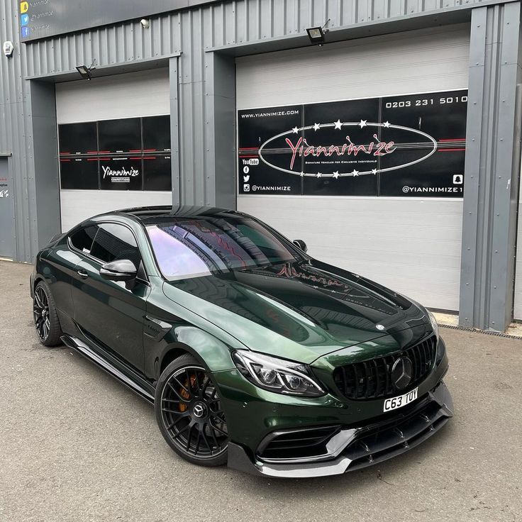 a green car parked in front of a garage