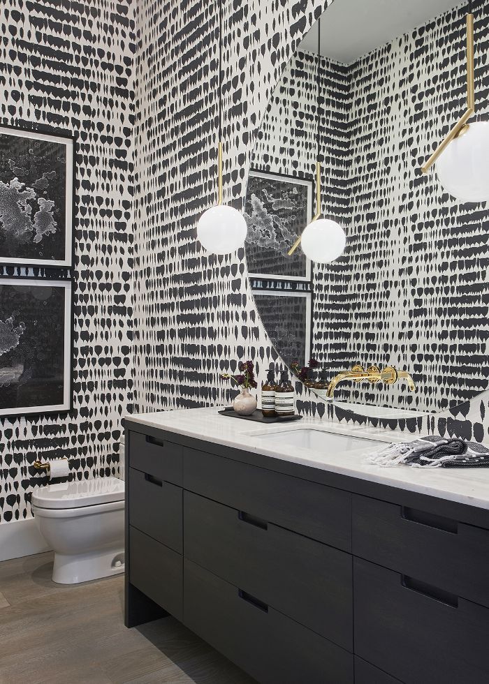 a bathroom with black and white wallpaper, two sinks and three lights on the vanity