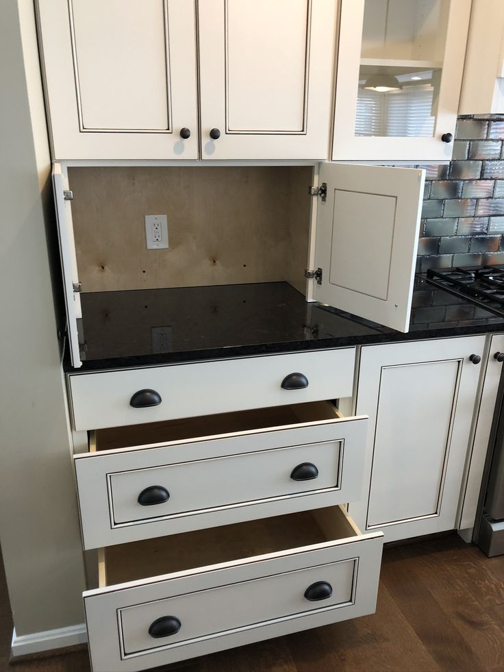 a kitchen with white cabinets and black counter tops