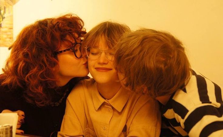 two women kissing each other while sitting at a table