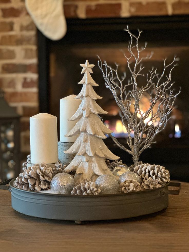 a christmas tree and candles on a tray in front of a fireplace