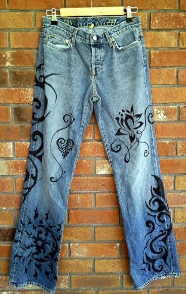 an old pair of jeans with floral designs on them hanging from a clothes line against a brick wall