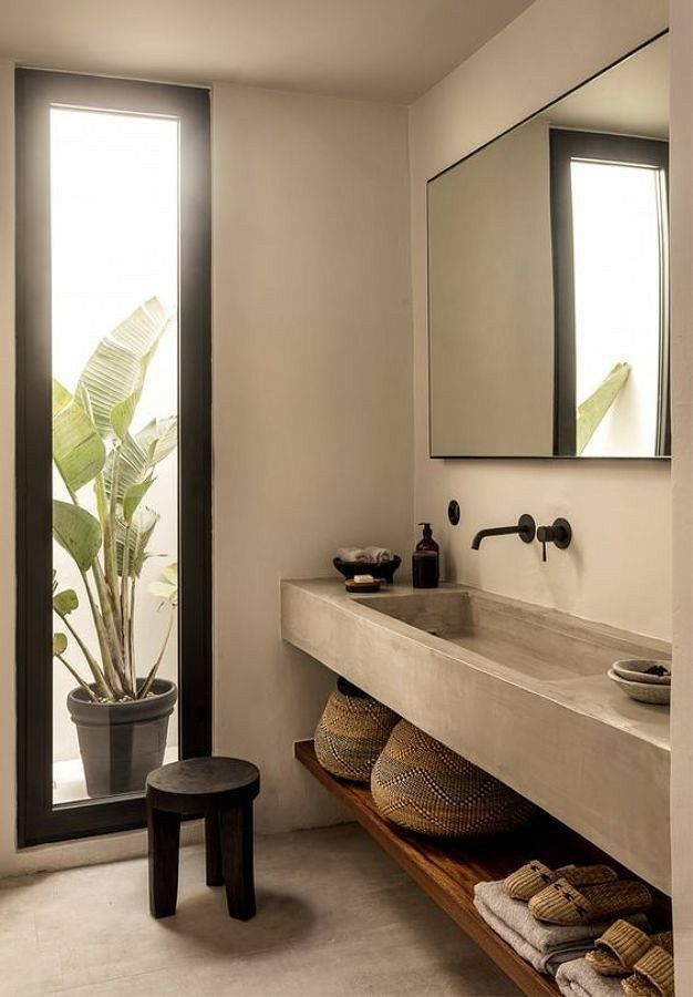 a bathroom with a sink, mirror and stool next to a plant in a pot