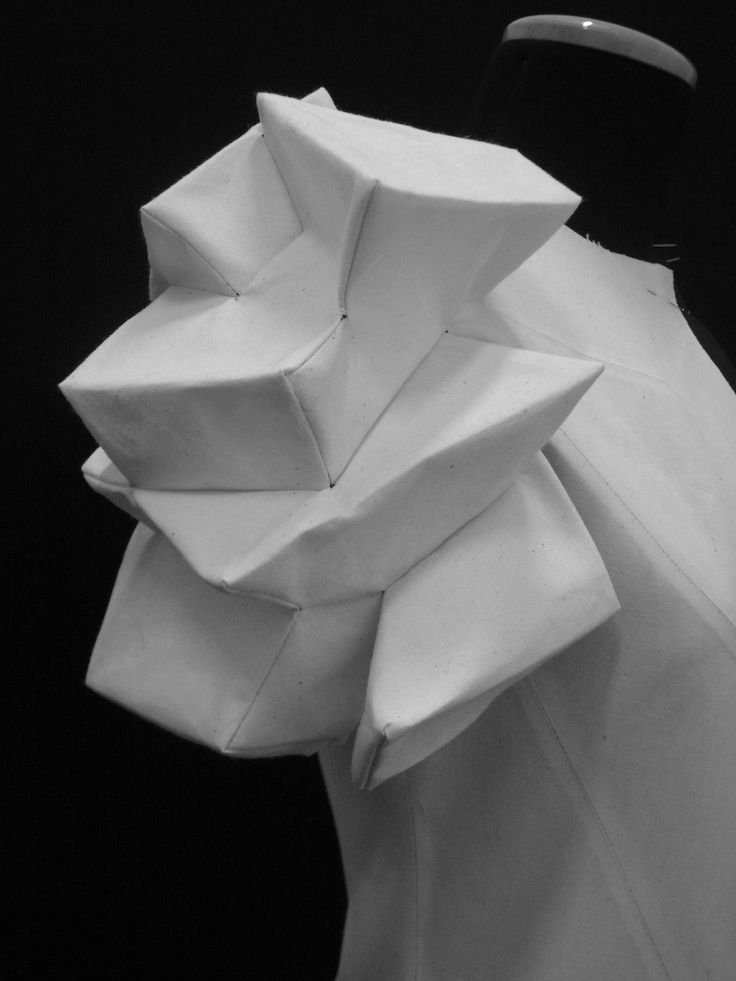 a black and white photo of a dress made out of folded paper on a mannequin's head