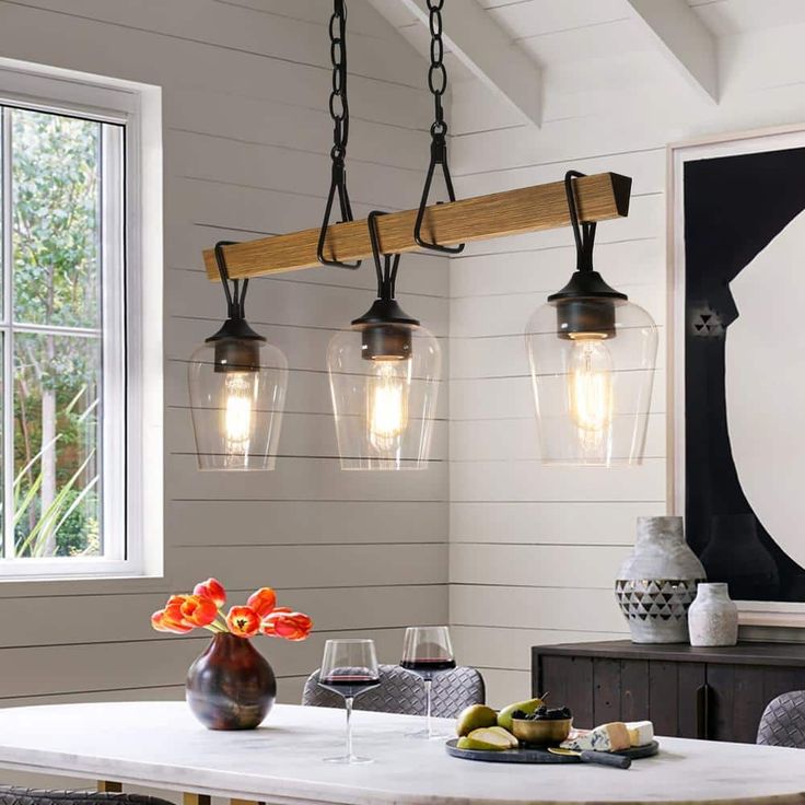 a dining room table with four lights hanging over it