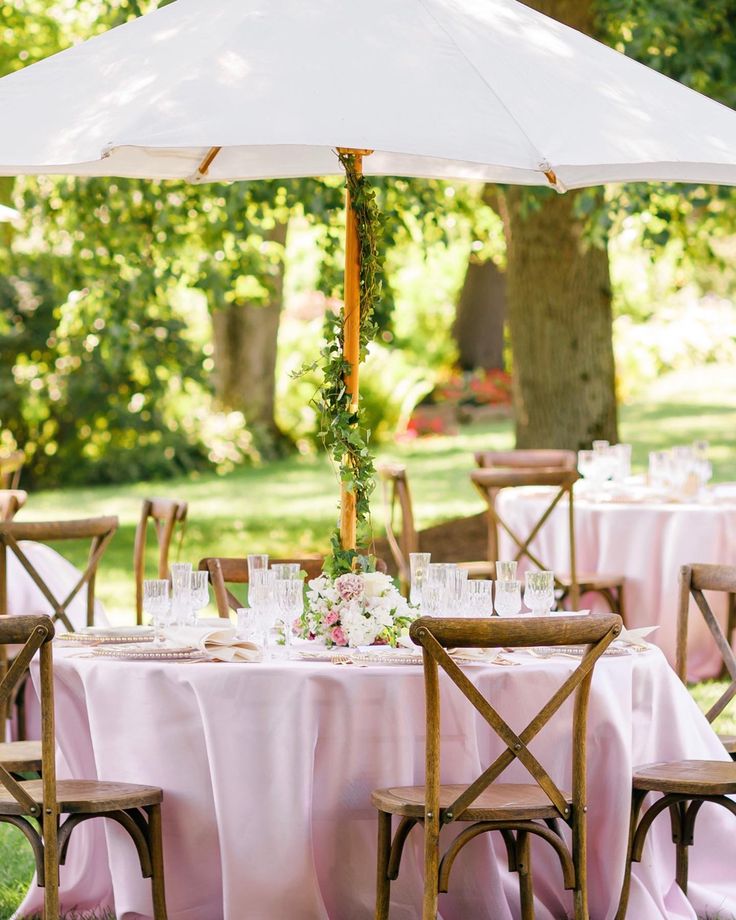 an outdoor table set up with pink linens and white tablescloths for a wedding reception