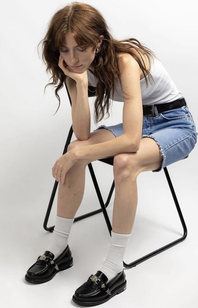 a woman sitting in a chair with her hand on her chin