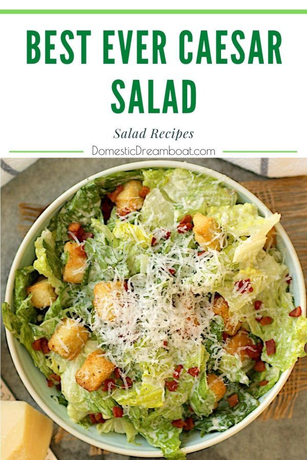 a salad with lettuce, croutons and cheese on top in a white bowl