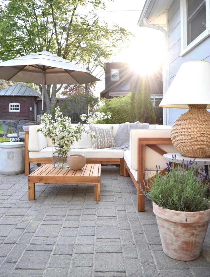 an outdoor living area with couches, tables and umbrellas in the sun light