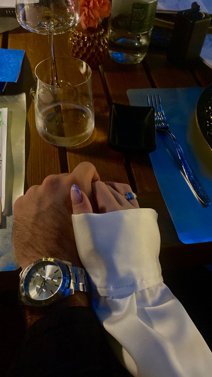 a man wearing a white tie sitting at a table with silverware and napkins