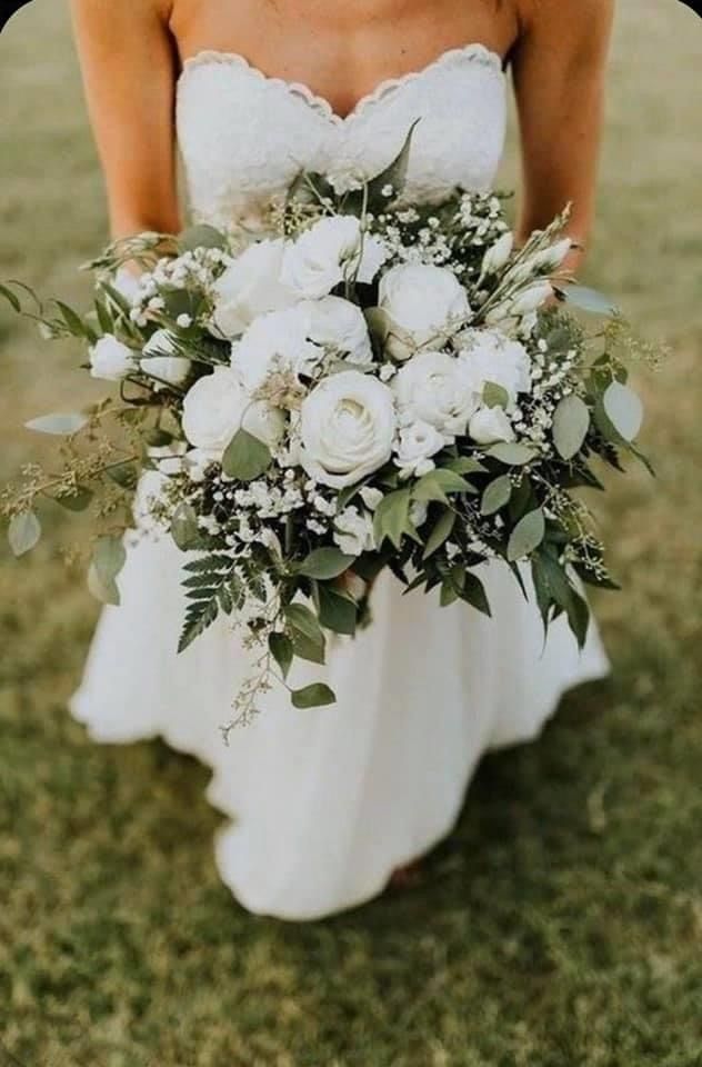 a bride holding a bouquet of flowers in her hand on the grass at their wedding