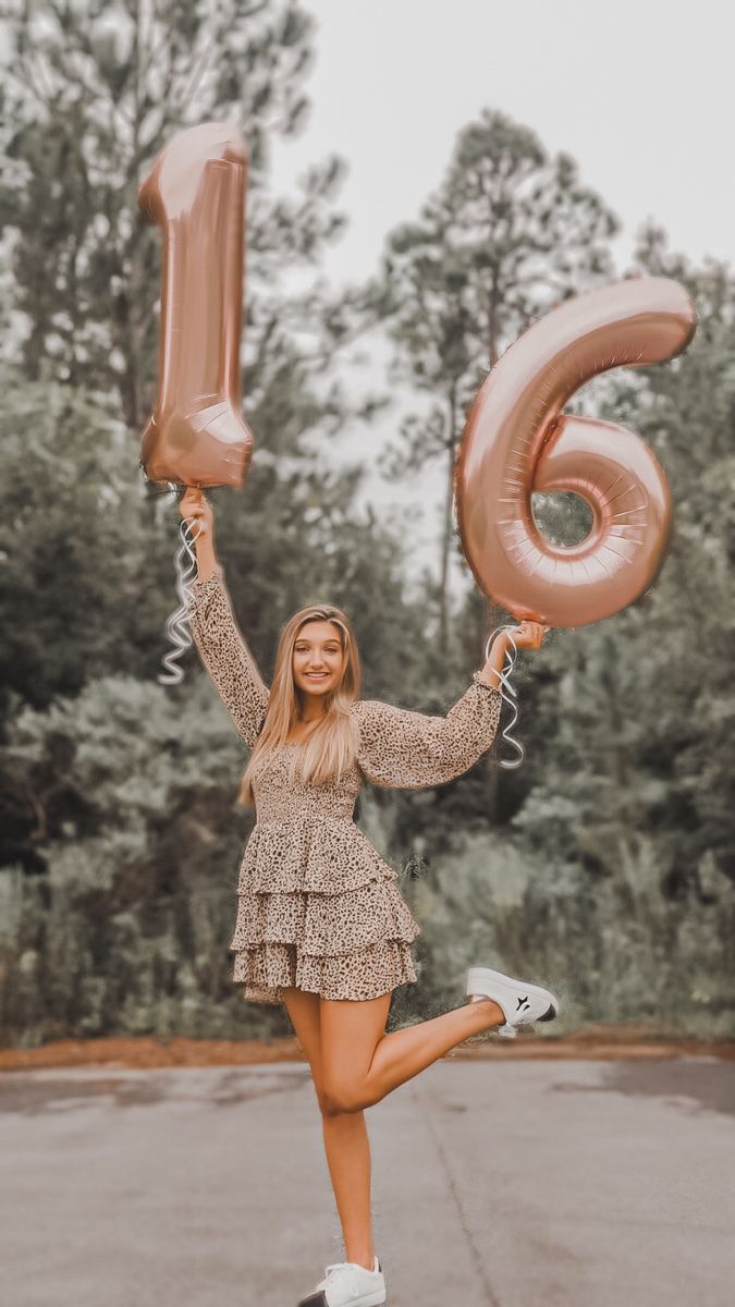 a woman is holding two large balloons and posing for the camera with her legs in the air