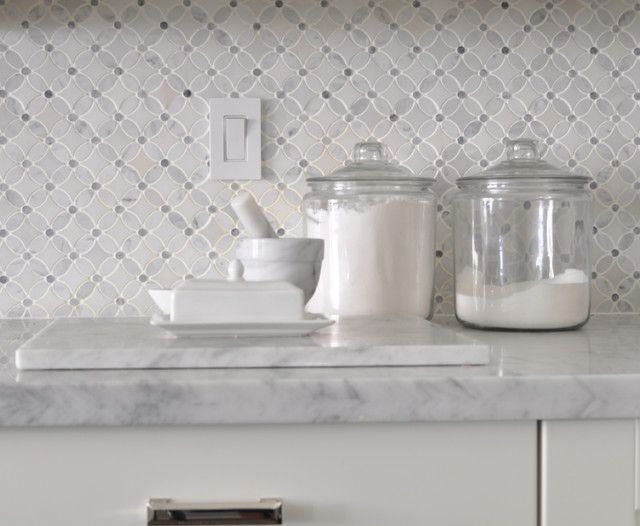 salt and pepper shakers sit on a marble countertop in front of a wallpapered backsplash