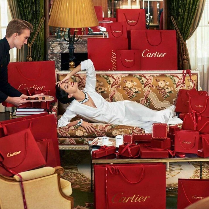 a woman laying on top of a couch surrounded by red bags