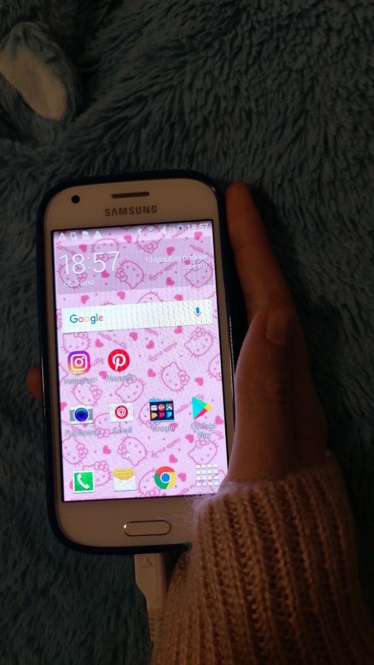 a person holding a cell phone in their hand on a blanket with the screen turned off