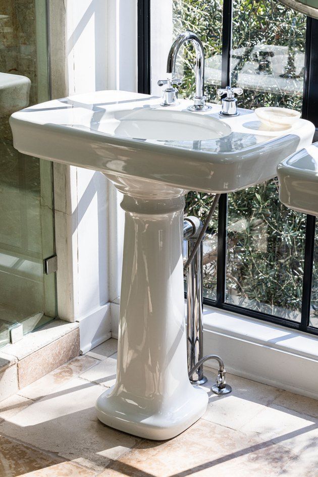 a white pedestal sink sitting next to a window