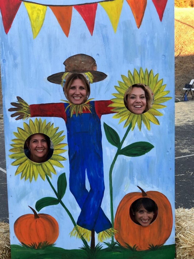 a painted scarecrow with sunflowers and two girls in the center, surrounded by hay