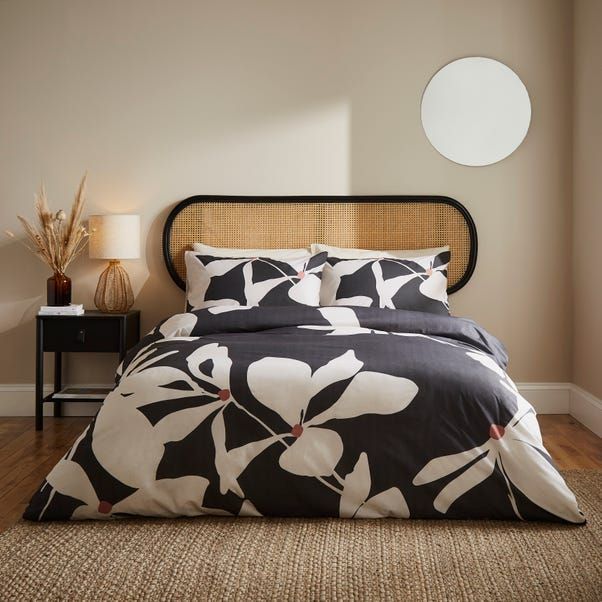 a bed with black and white comforter in a bedroom next to a night stand