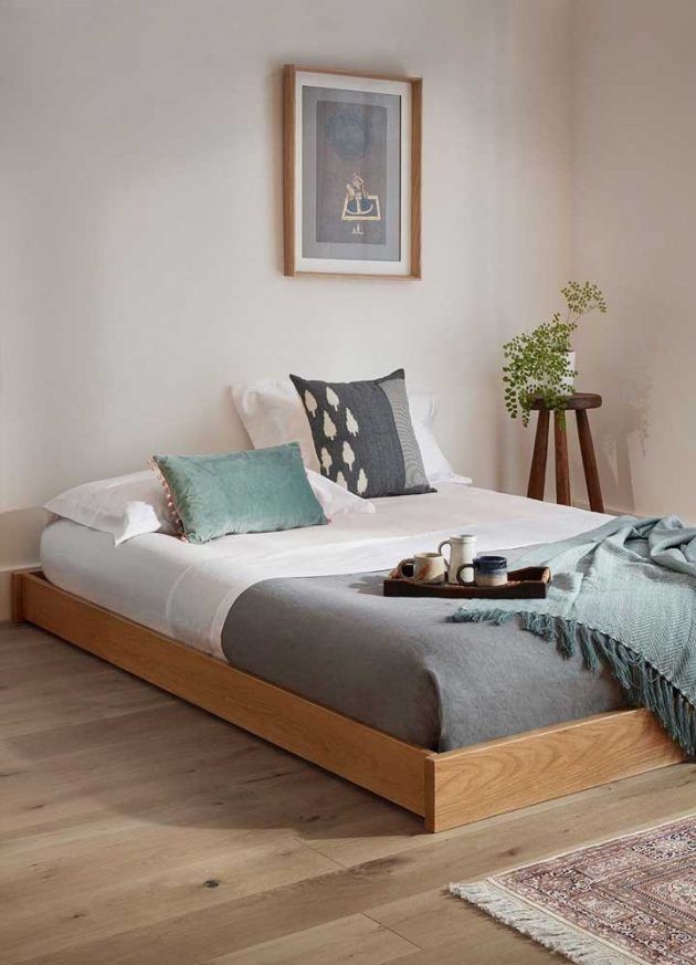 a bed sitting on top of a wooden floor next to a window