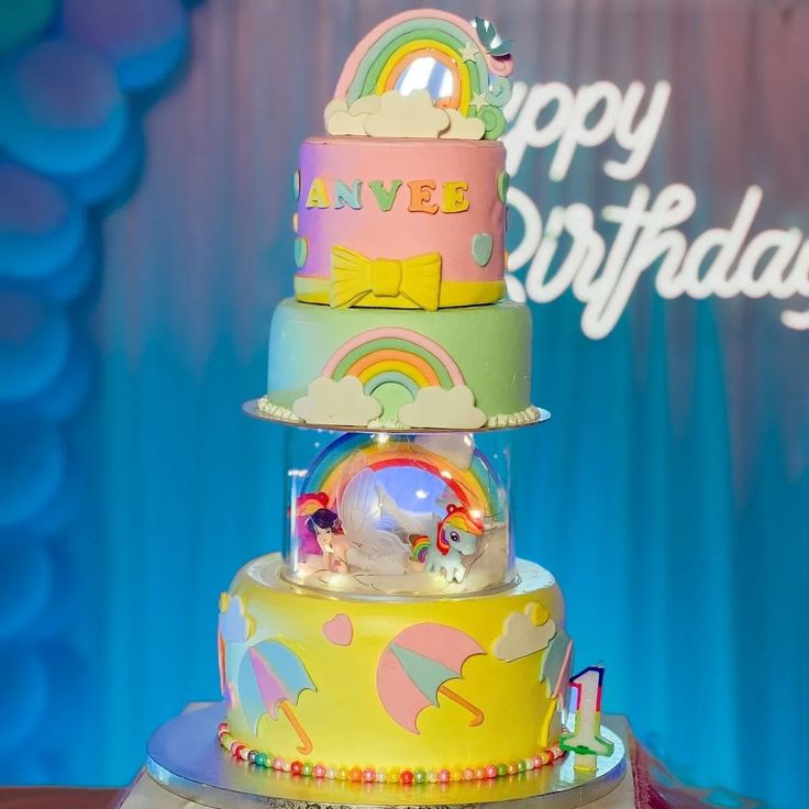 a three tiered cake decorated with rainbows and clouds