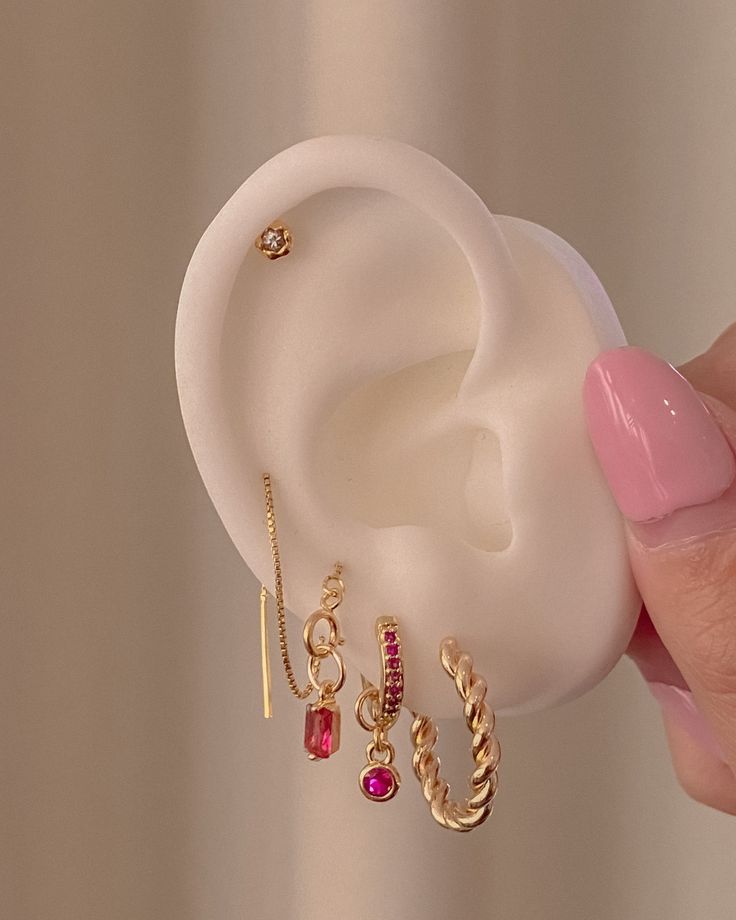 a person holding an earring in their right hand and two different earrings on the other