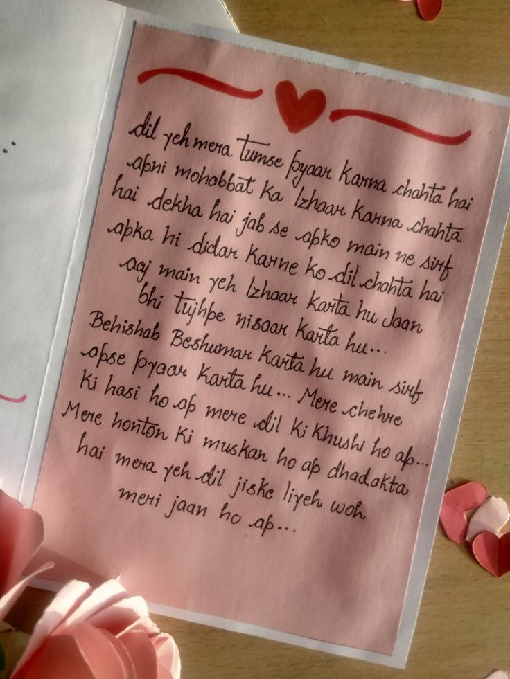 a piece of paper with writing on it next to pink flowers and hearts in the background