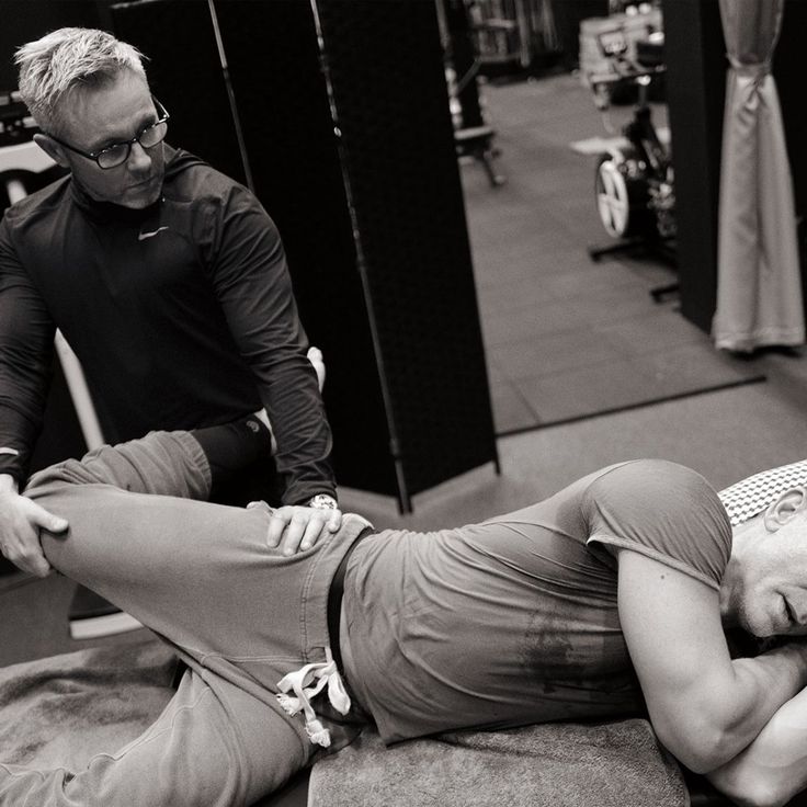 a man is laying on the floor with his leg up in front of him and another person standing behind him