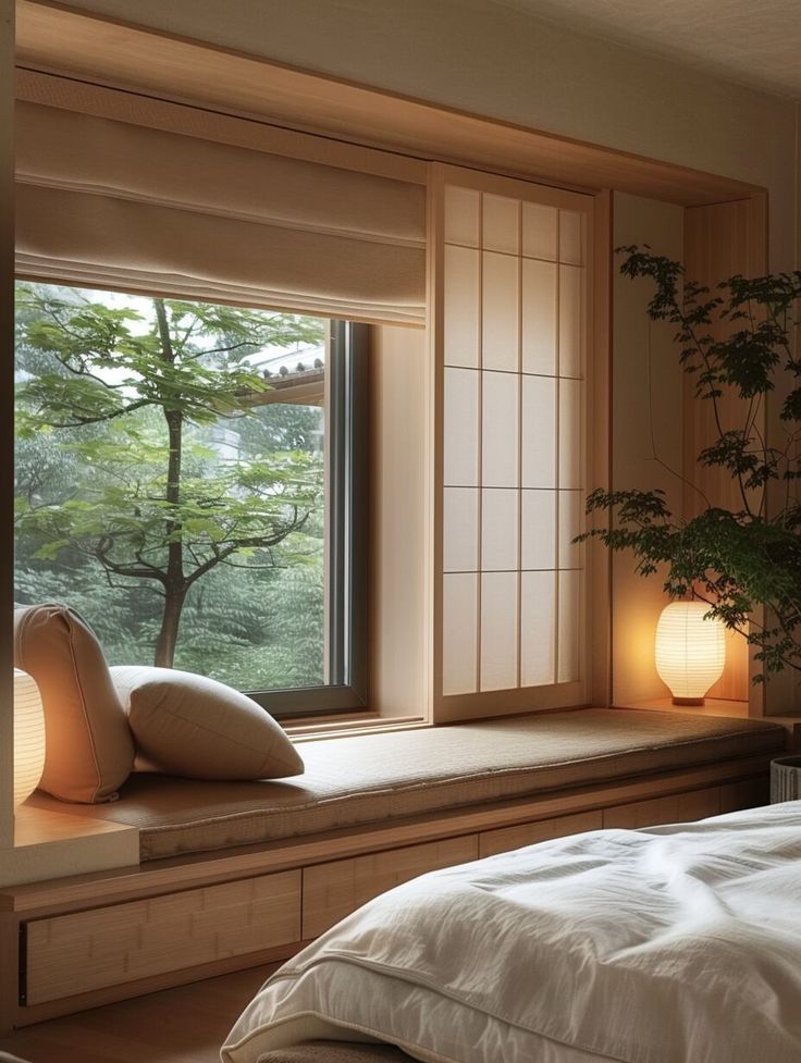 a bed sitting under a window next to a plant in a room filled with windows