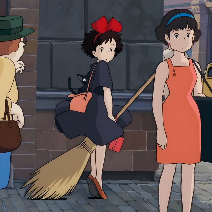 three women are standing on the sidewalk with brooms in hand and one woman is holding a cat