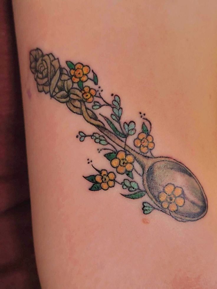 a woman's thigh with flowers and a spoon tattoo on her side ribcage