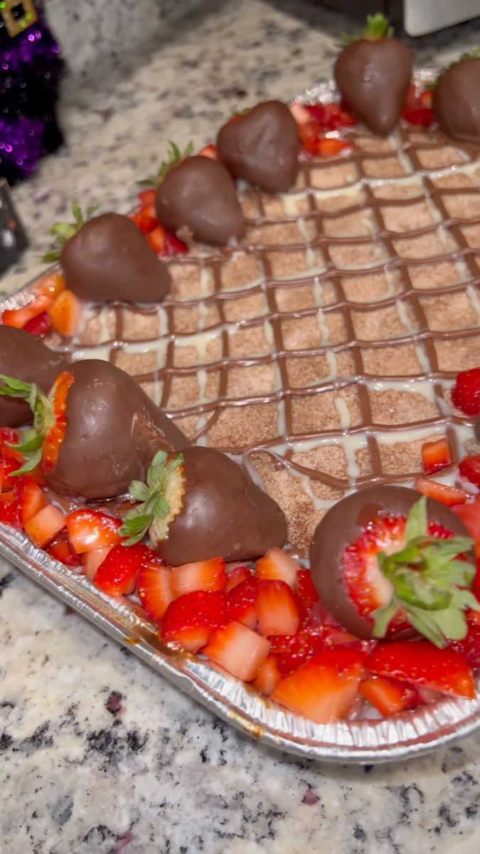 a heart shaped cake with strawberries and chocolate covered strawberries on the top, sitting on a marble countertop