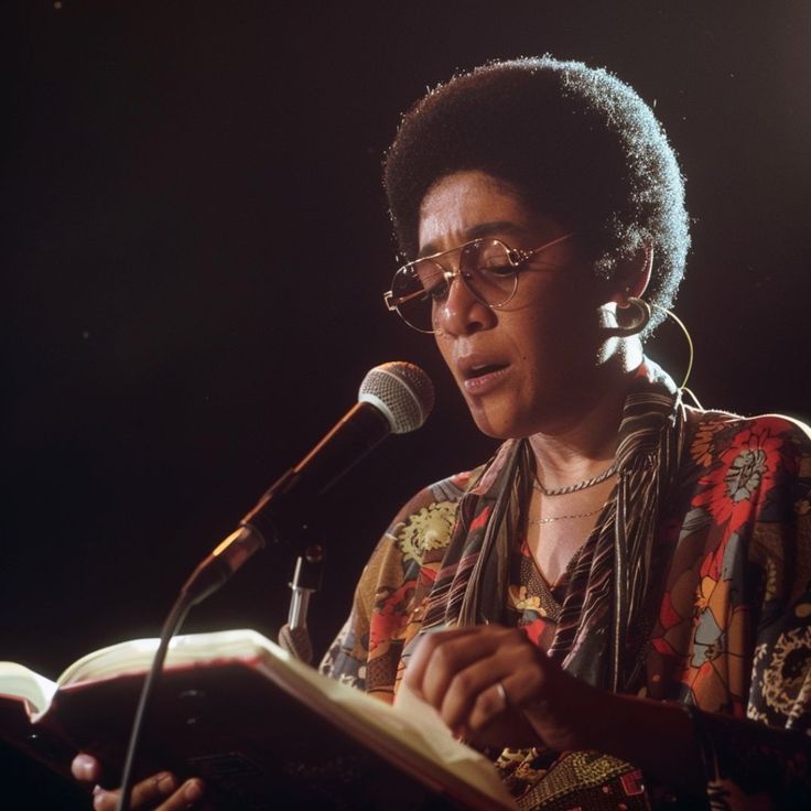 a woman reading a book in front of a microphone