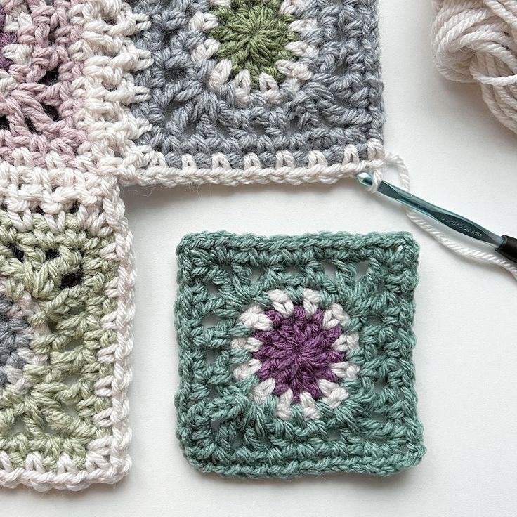 four crocheted squares sitting on top of each other with yarn in the middle