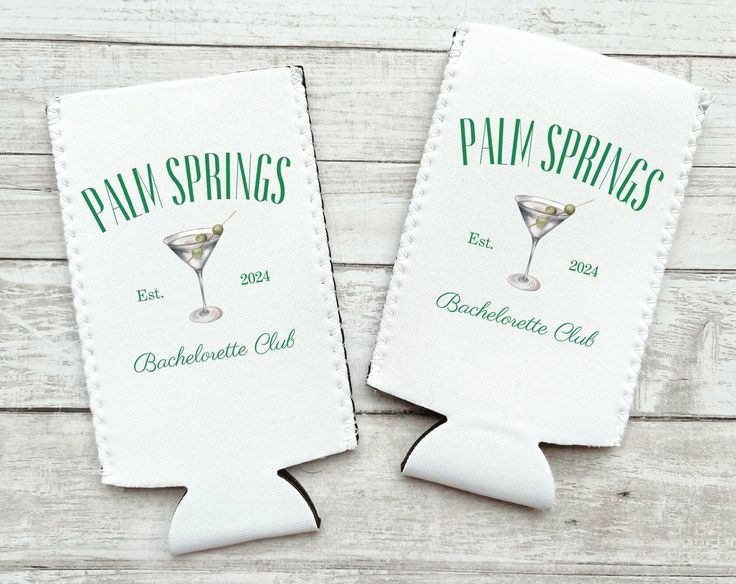 two white paper napkins with green lettering on the front and back of each one