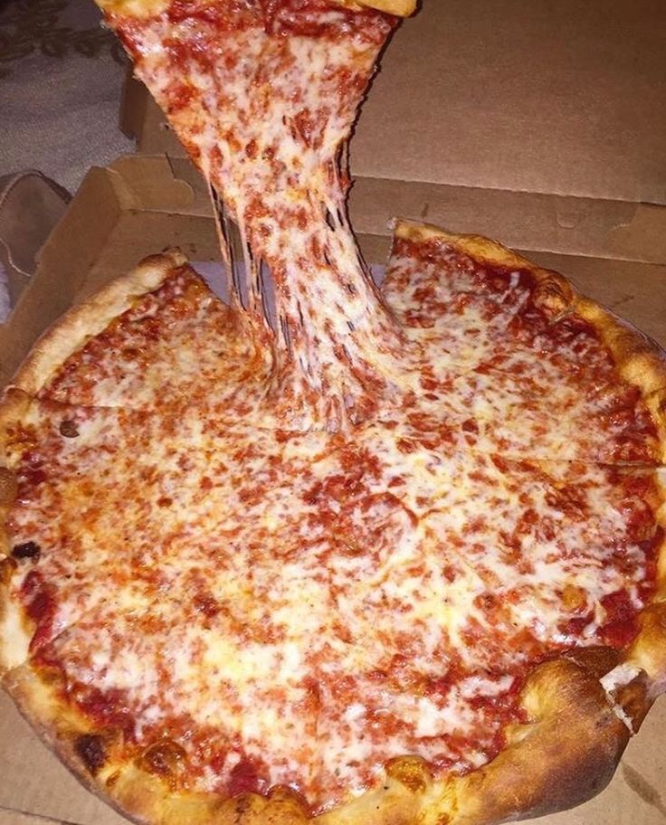 a pizza with cheese being cut into slices