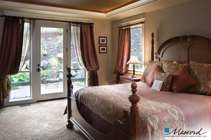 a large bed in a bedroom next to two windows with french doors leading into the outside