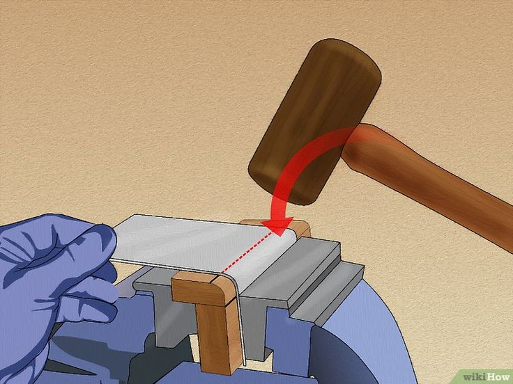 a hammer hitting a piece of wood on top of a table with blue gloved hands