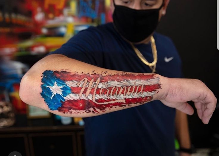 a man wearing a face mask and covering his arm with an american flag tattoo