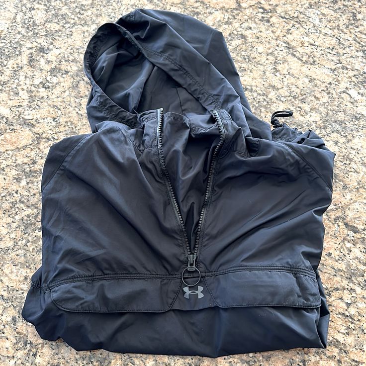 a black jacket laying on top of a stone floor next to a bag with zippers